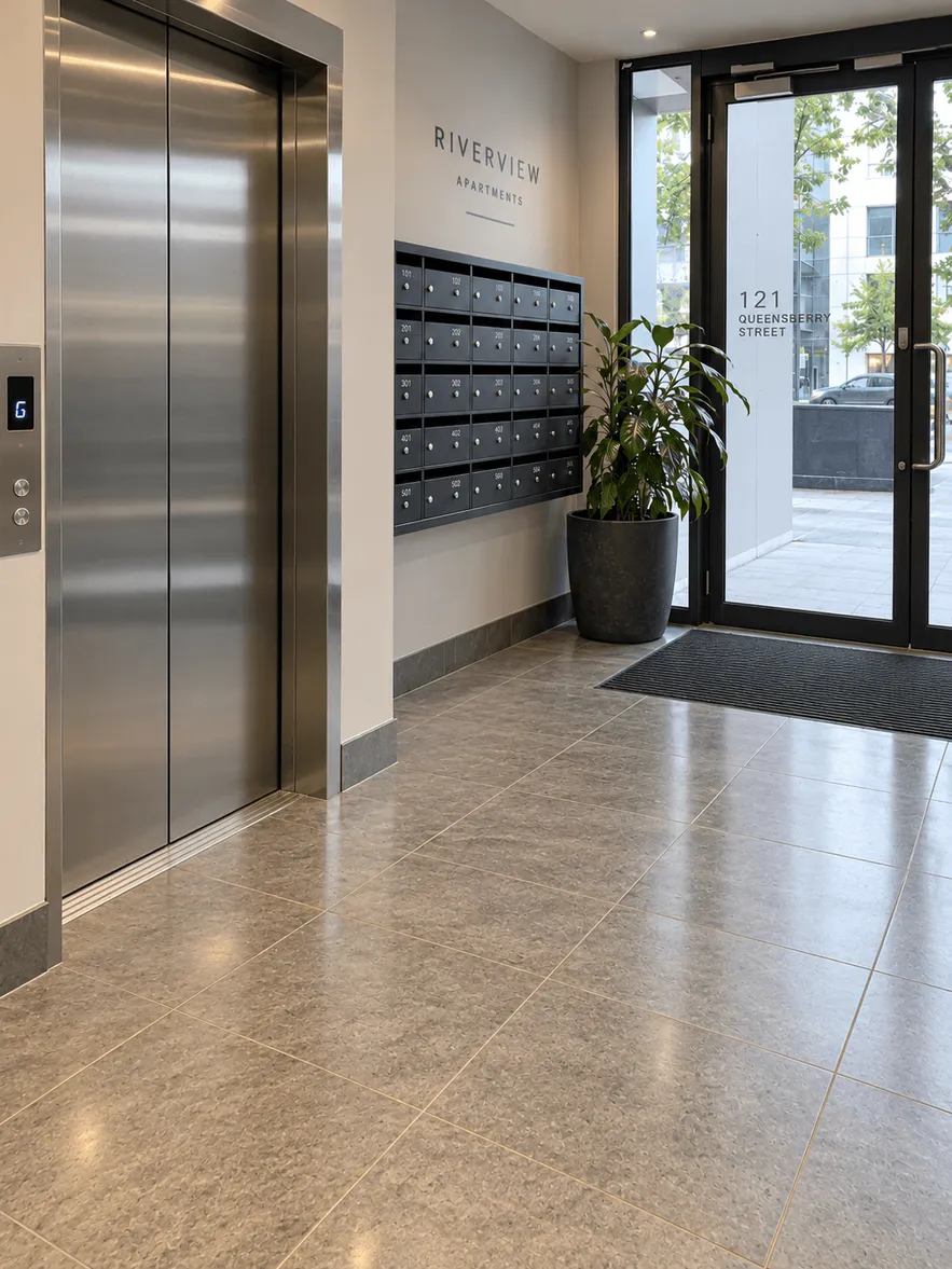 Same apartment lobby with polished lift doors, tidy mailboxes and a glossy, clean floor after a commercial clean