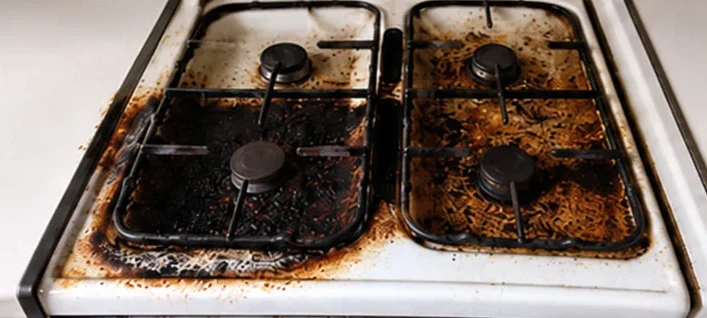 Gas cooktop caked in burnt-on grease before an end of lease clean
