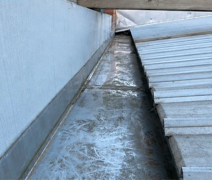 Same box gutter cleared of moss and debris with a clean, free-flowing channel