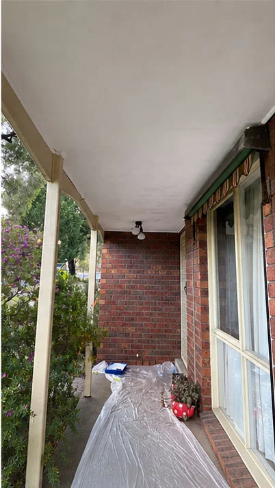 Brick home veranda with drop sheets laid out and posts and ceiling prepared before painting