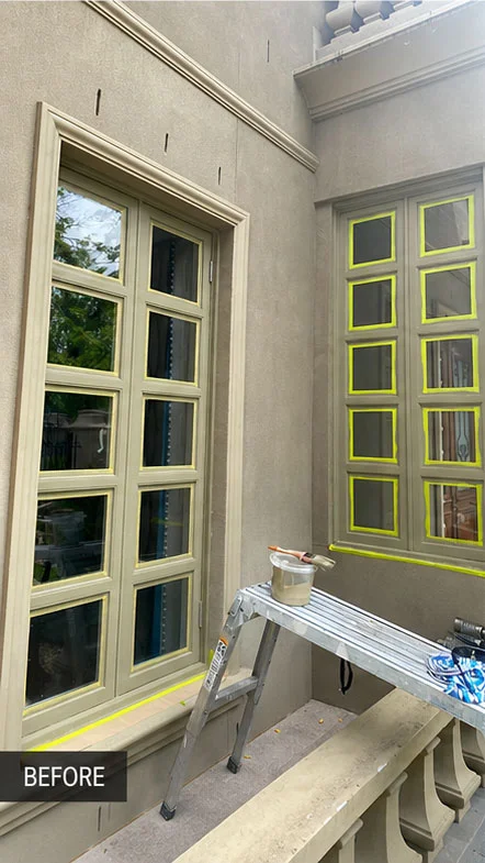 Exterior timber window frames masked with tape and a painter's platform set up before repainting