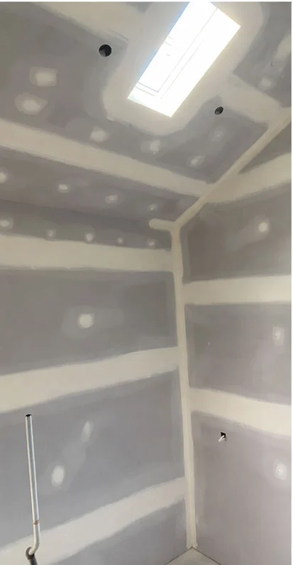 New plasterboard walls and raked ceiling with filled joints and screw holes before painting