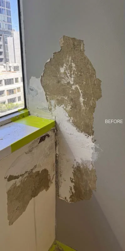 Damaged wall and window reveal with stripped plaster and exposed patches before repair